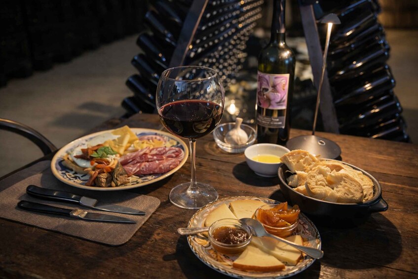 A table with a wine glass, plates of food, a bottle of wine, and a candle. 3