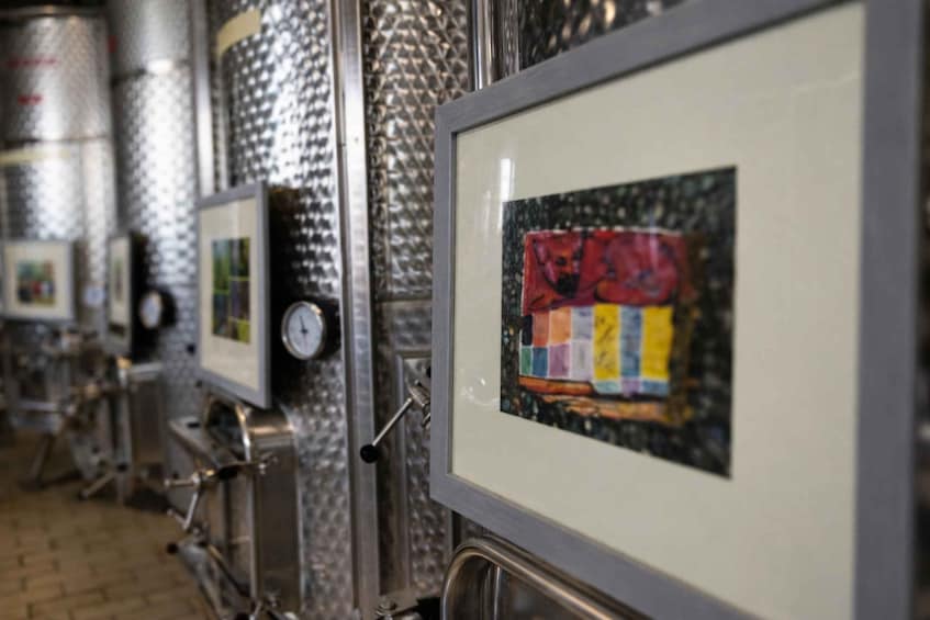 A row of framed artworks on a metallic wall in a public space. 4