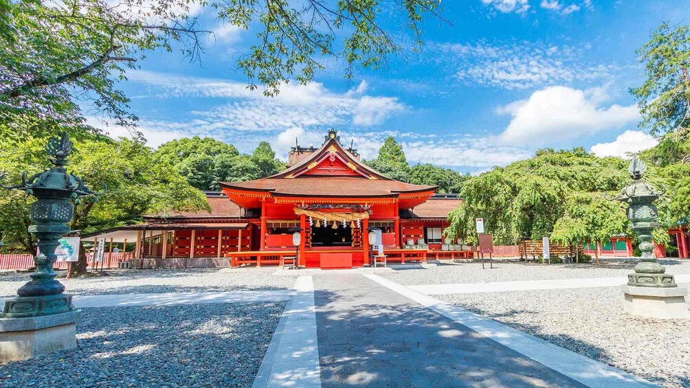 A traditional Japanese temple with a red roof, surrounded by trees and gravel paths. 4