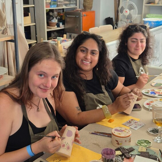 Three people painting on pottery. 4