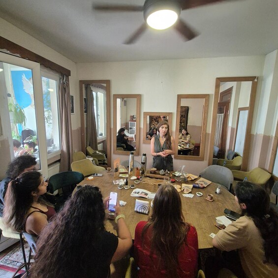 A group of people seated around a wooden table in a room with mirrors on the walls, engaged in a meeting or discussion. 5