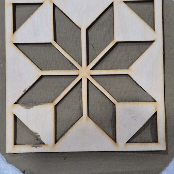 A geometric wooden panel with a central star-like design and surrounding triangular shapes. 3