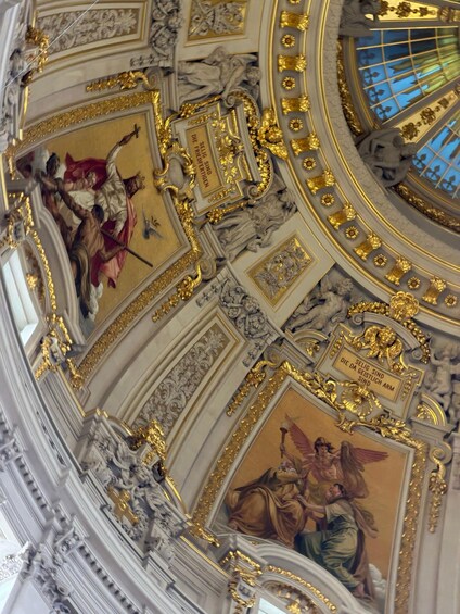 A detailed ceiling with ornate gold decorations and classical frescoes. 2