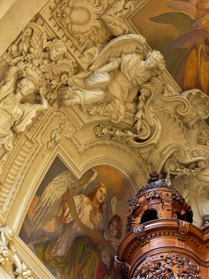 An ornate ceiling with intricate carvings and a mural of an angelic figure. 5