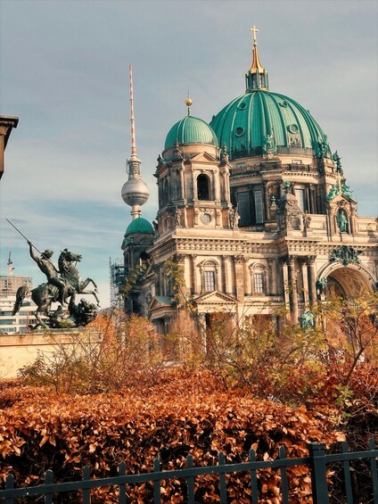 A historic building with a green dome and a statue of a horseman. 1