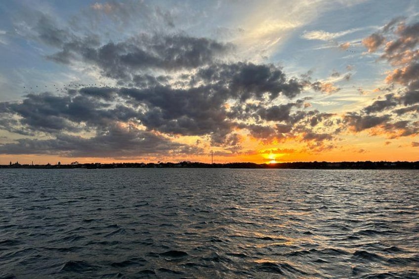 Een zonsondergang boven een wateroppervlak met wolken aan de hemel. 4