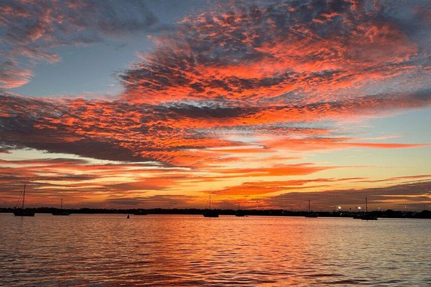 Een zonsondergang boven een wateroppervlak met een stadsachtergrond in de verte. 1