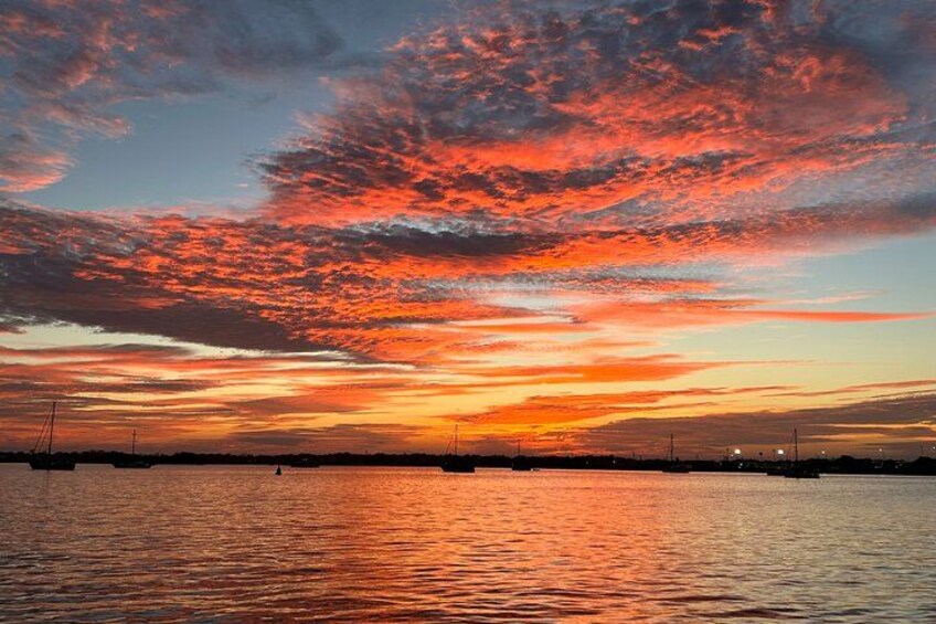 Un coucher de soleil sur une étendue d'eau, avec une ligne d'horizon visible au loin. 1