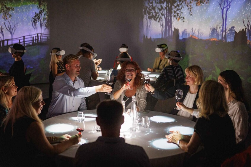 A group of people seated around a table with glasses of wine, engaged in conversation. 1