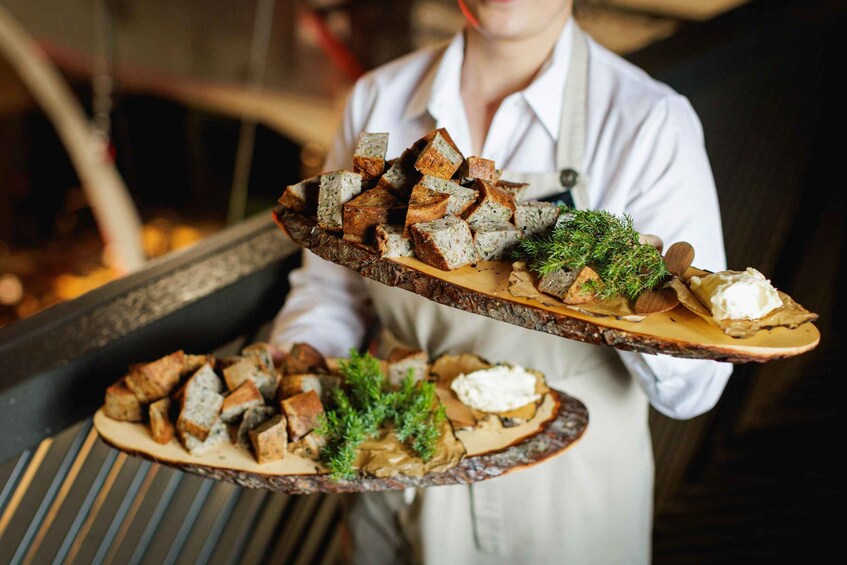 A person holding two wooden boards with food. 4