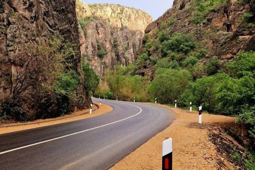 Una carretera sinuosa atraviesa un cañón con acantilados rocosos y vegetación escasa. 3