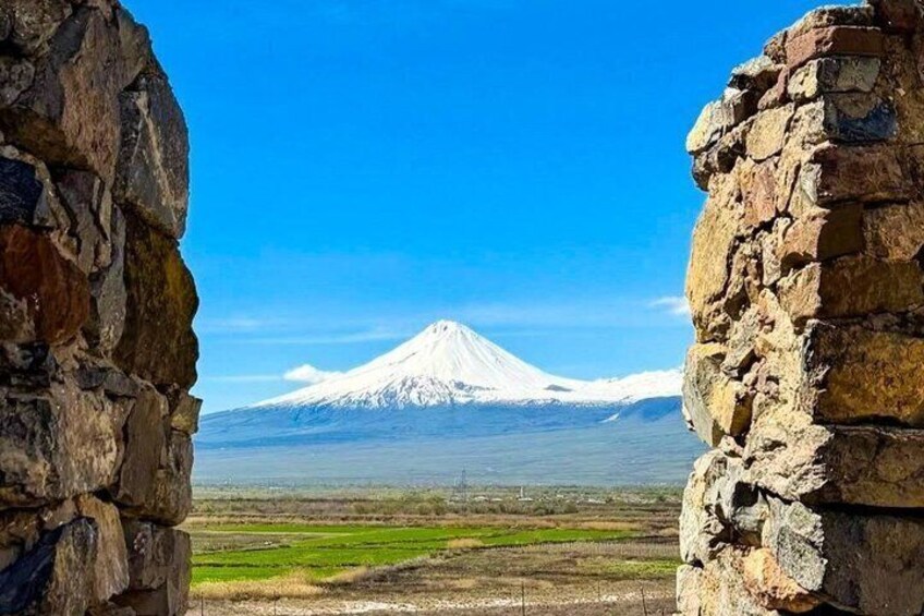 Un monte nevado, un muro de piedra y un campo verde. 4