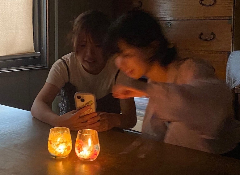 Two people sitting at a table with lit candles and a smartphone. 4