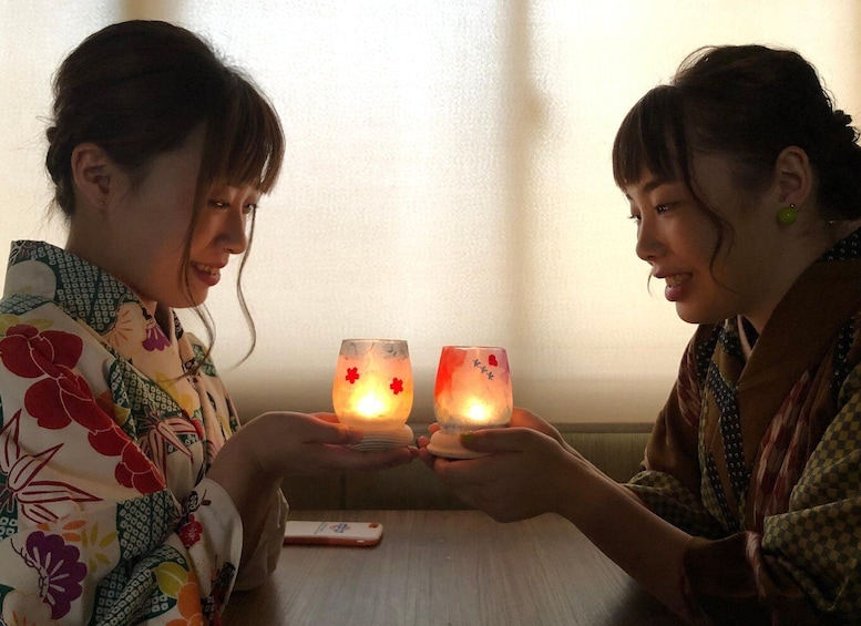 Two people holding lit candles with floral designs. 2