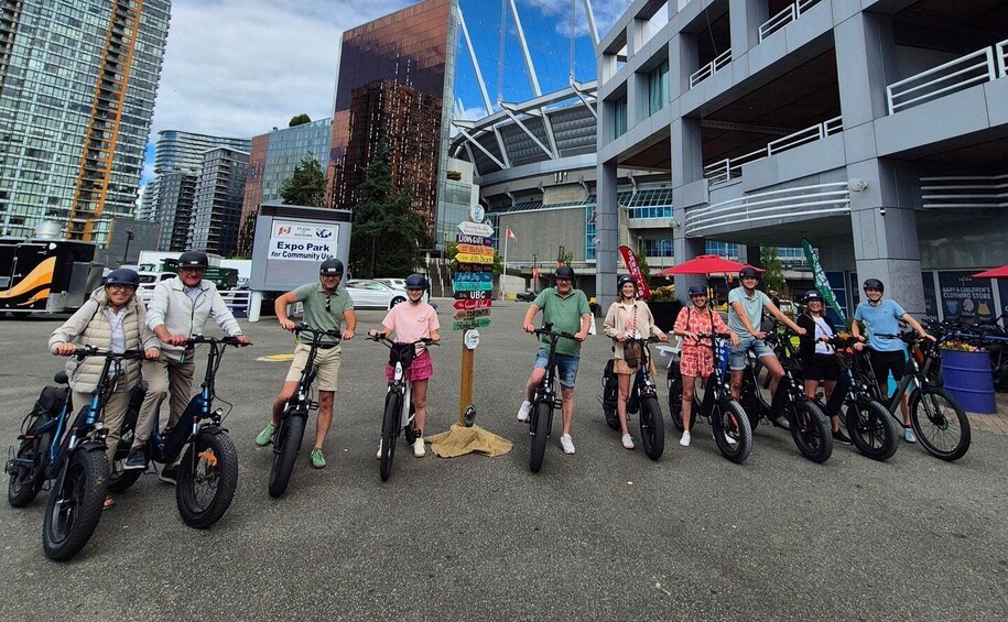 A group of people on bicycles in an urban setting with modern buildings and a sign for Expo Park. 2