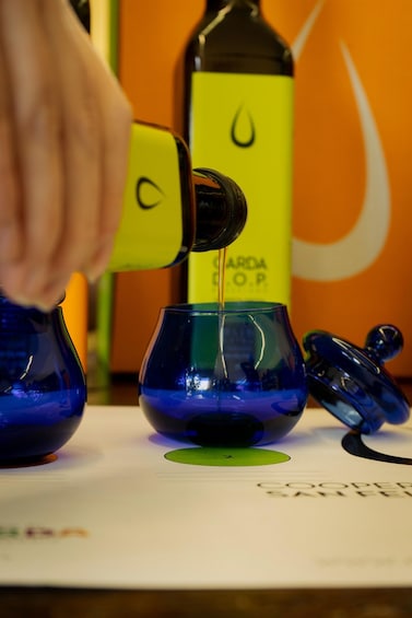 A hand pouring a dark liquid from a yellow bottle into a blue glass. 4