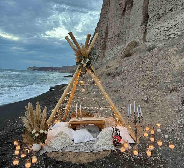 A beach setting with a wooden structure, candles, and a blanket. 3