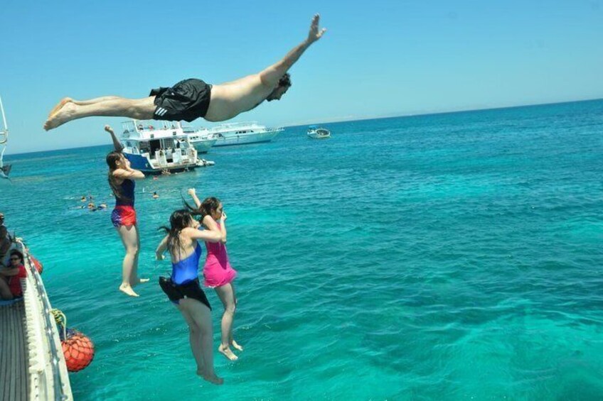 Des gens sautent d’un quai dans une eau océanique d’un bleu turquoise. 2