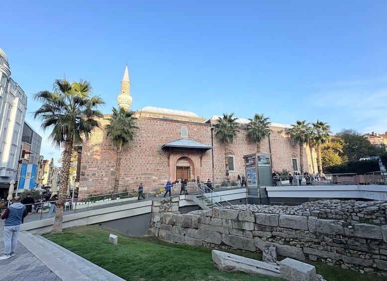 A historic building with a dome and minaret, surrounded by palm trees and a stone wall. 5