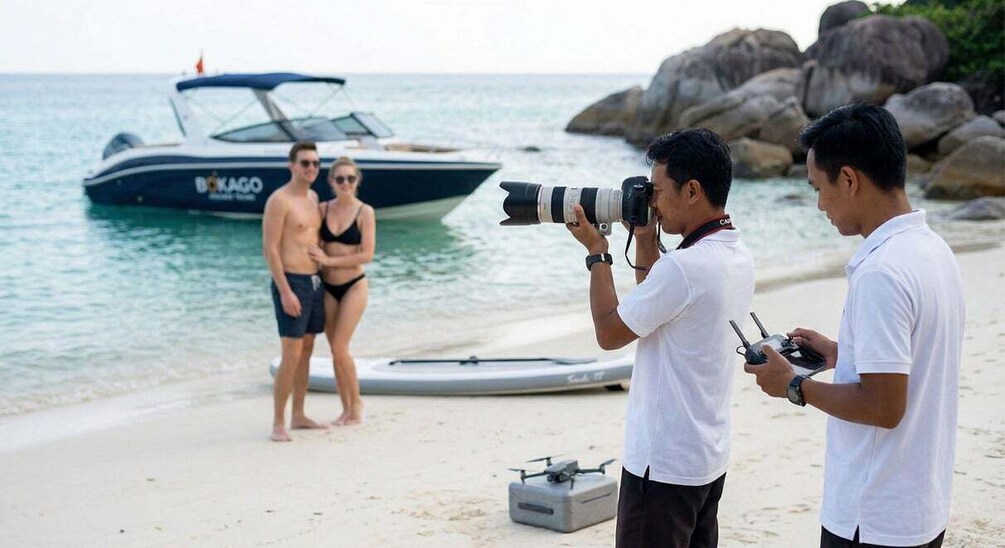 A beach with a boat named 'BOKAGO' and a person operating a drone. 5