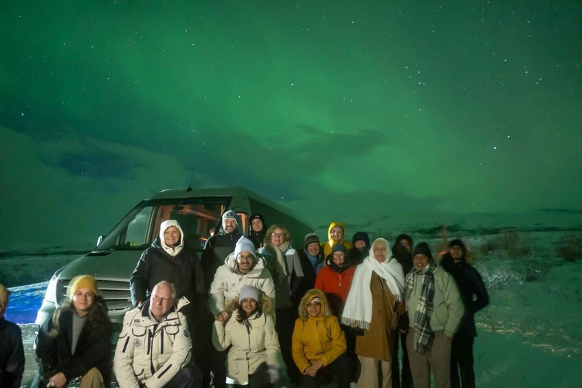 A group of people posing with a vehicle under a night sky with visible stars. 5