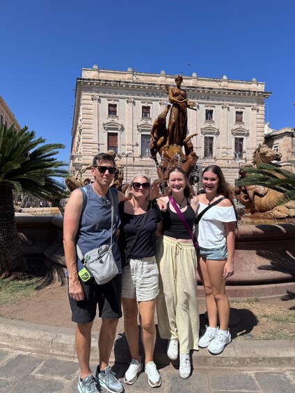 Un grupo de personas posando frente a un edificio histórico con una estatua. 5