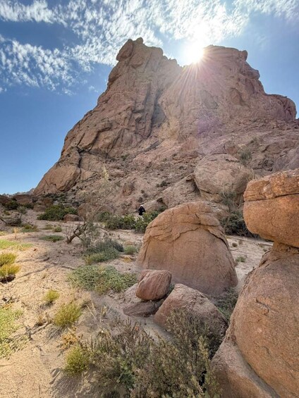 A rocky desert landscape with a prominent cliff and a person hiking. 1