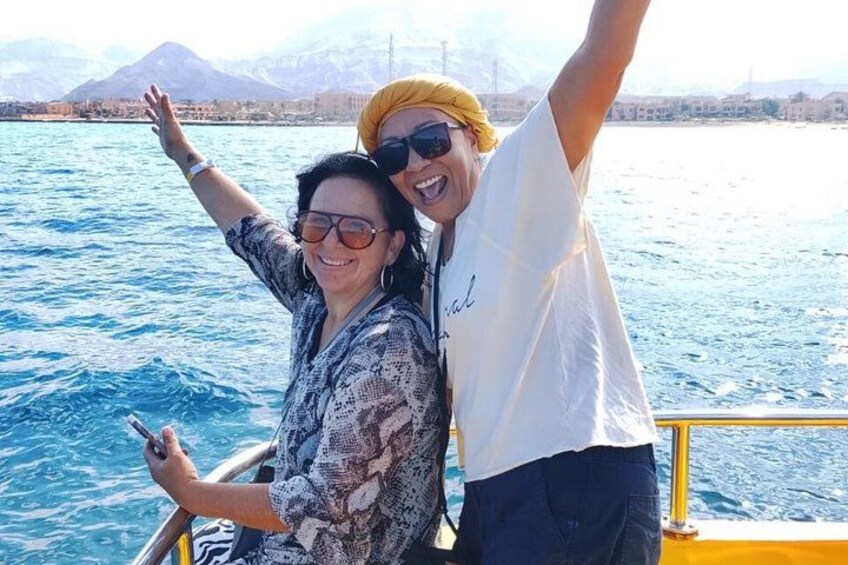 Two people on a boat with a mountainous landscape in the background. 1