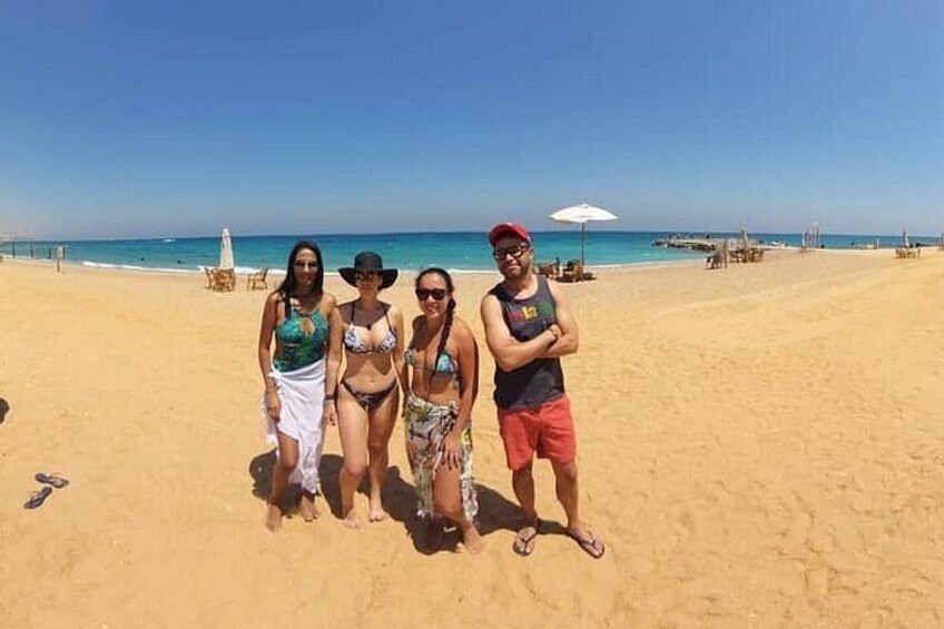 A sandy beach with a clear sky, a few umbrellas, and a calm sea. 3