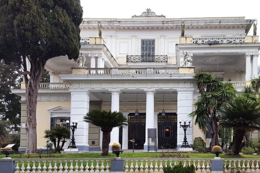 A grand classical building with columns, a large tree, and well-maintained gardens. 5