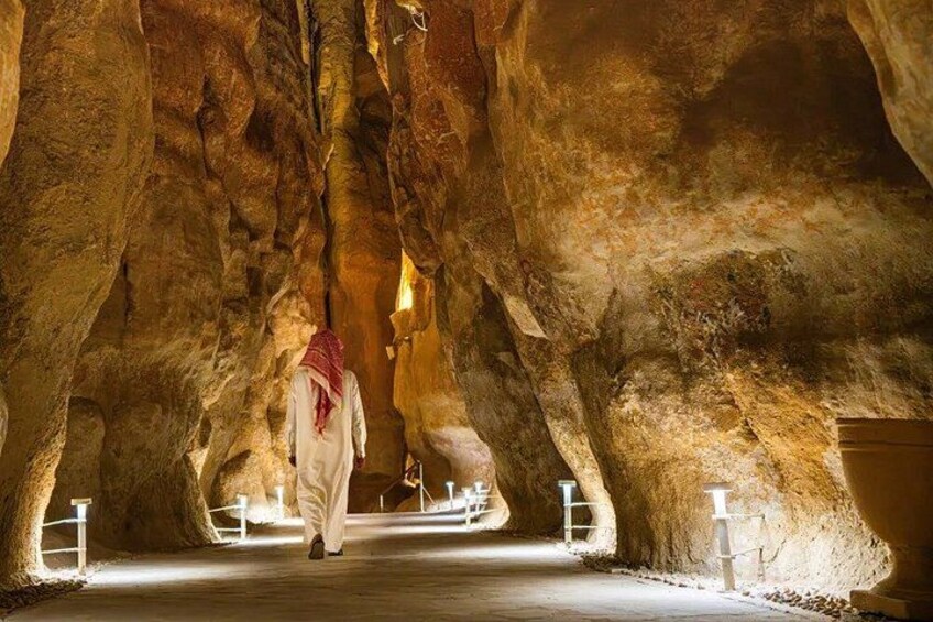 A person walking through a cave with stalactites and a red cloth draped over their head. 1