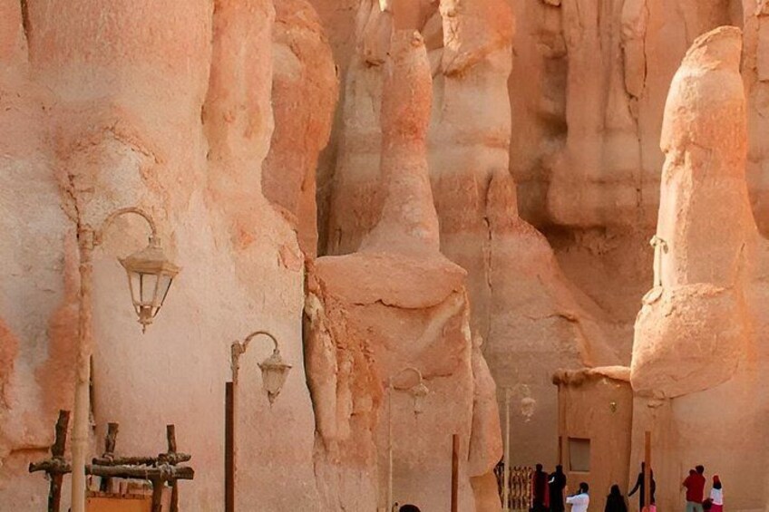 A rock formation with carved figures, a wooden bench, and a hanging lantern. 2