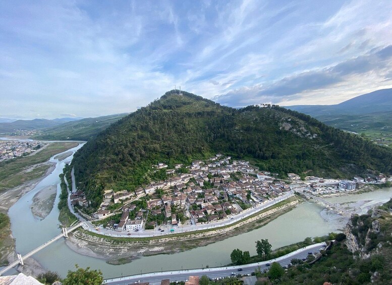 A town nestled in a valley with a river, surrounded by hills and a bridge crossing the river. 3