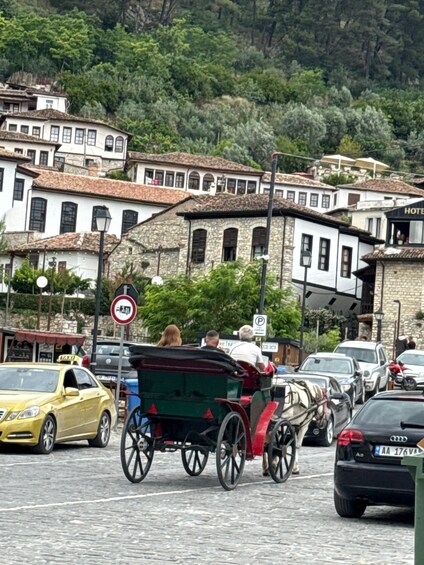 A cobblestone street with a horse-drawn carriage, parked cars, and traditional buildings. 5