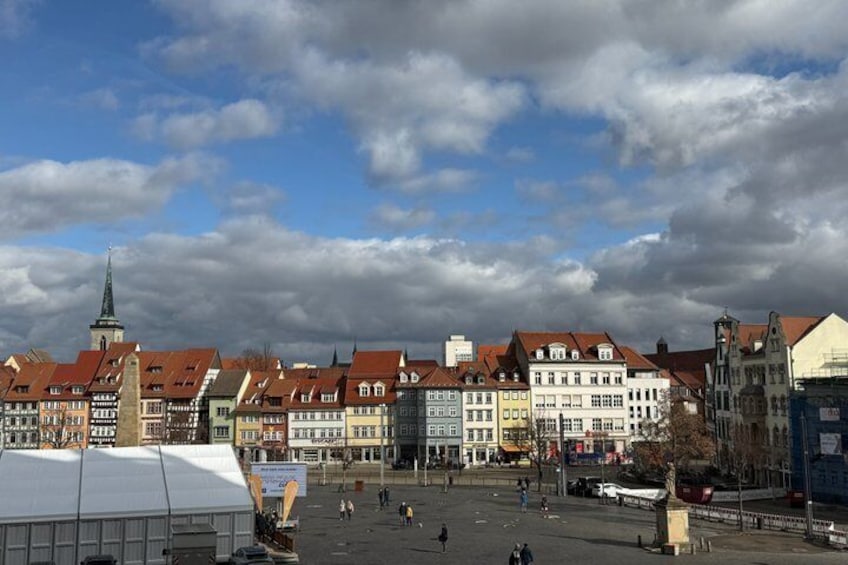 A historic town square with traditional buildings and a prominent church spire. 4