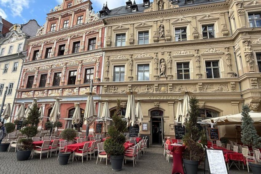 A historic building with ornate architecture, outdoor seating, and potted plants. 2