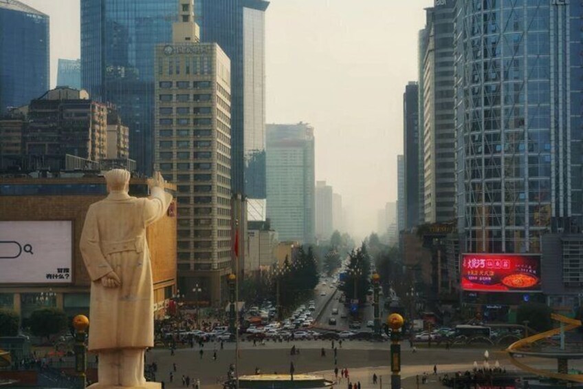 A cityscape with tall buildings, a statue, and a busy street. 3
