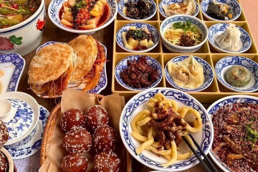 A variety of dishes arranged on a tray, including what appears to be sushi, dumplings, and other Asian cuisine. 2