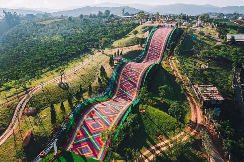 Eine farbenfrohe Fußgängerbrücke über einem Tal mit üppiger Vegetation und weit entfernten Hügeln. 1