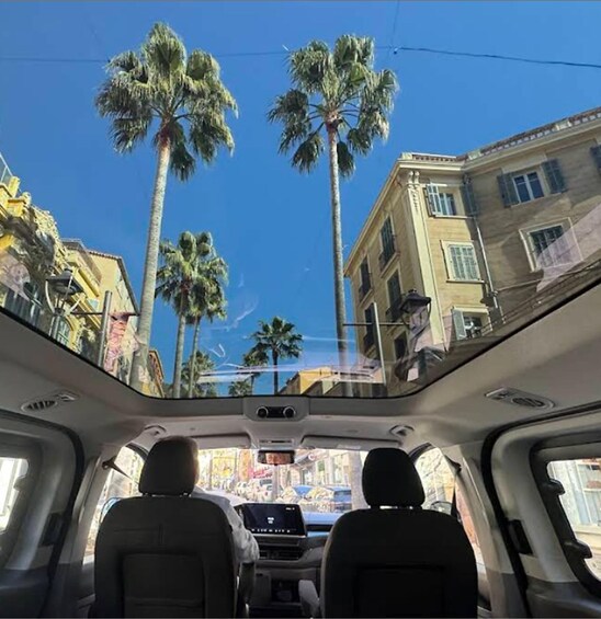 A vehicle's interior with a view of palm trees and buildings through the sunroof. 5