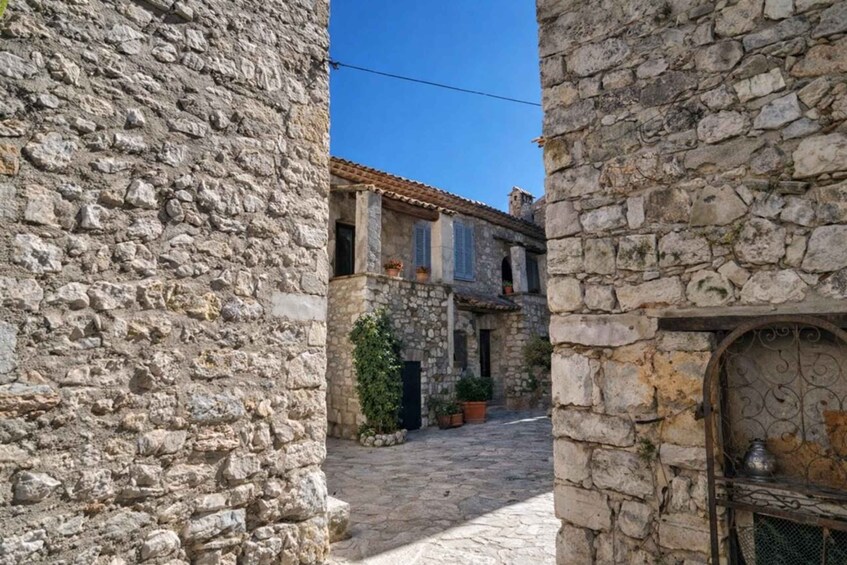 A narrow stone street flanked by old stone buildings with a clear blue sky above. 2