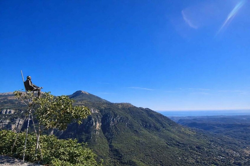 A person sitting on a rock with a mountain range in the background. 3