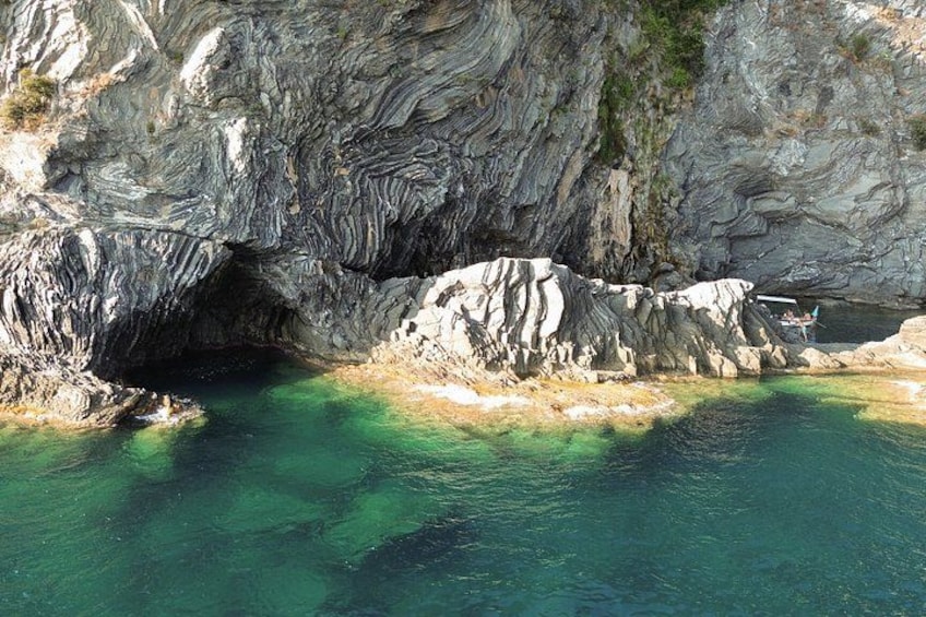 A rocky coastal landscape with clear turquoise water and a cave entrance. 5