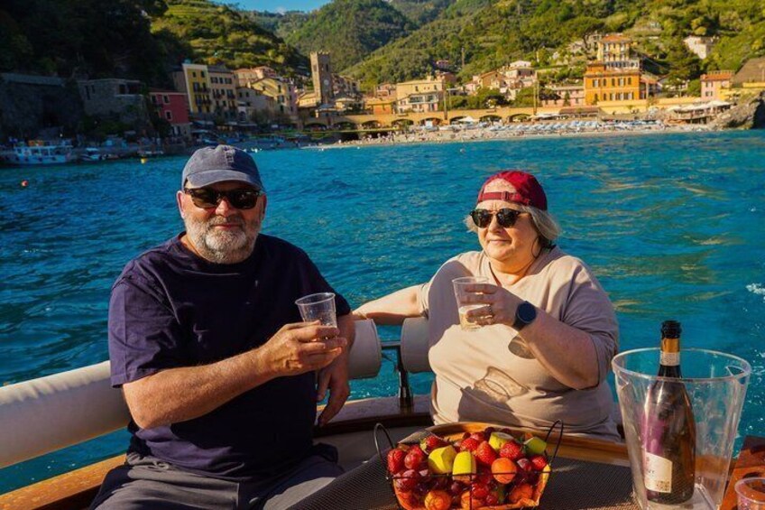 Two people on a boat with a basket of fruit and a bottle of wine. 3
