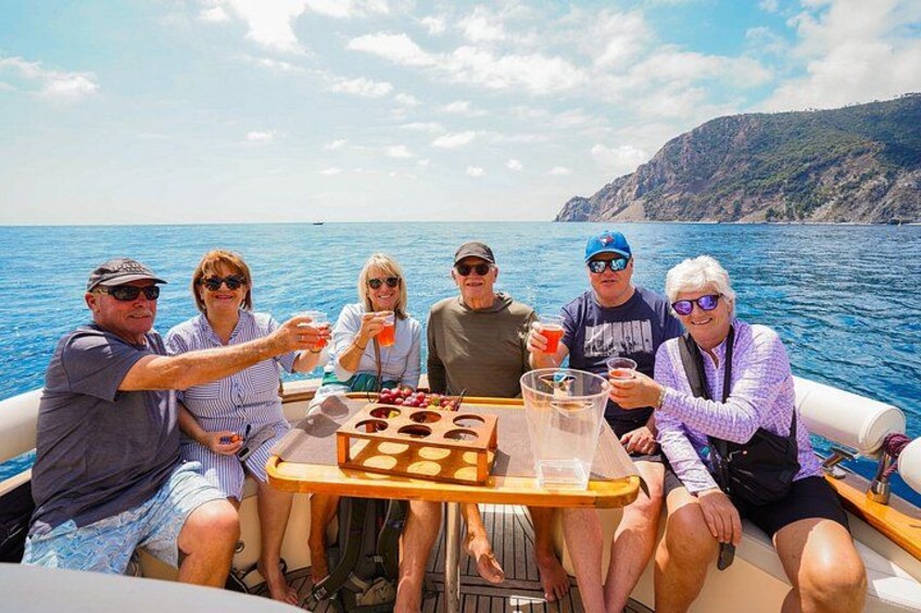 Un grupo de personas en un barco con una mesa en el centro, rodeado de agua y un paisaje montañoso al fondo. 3