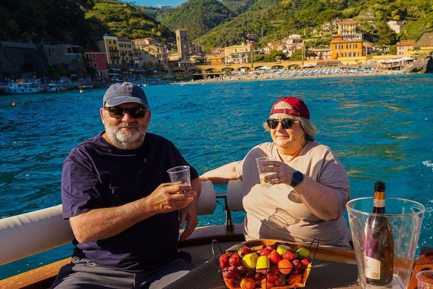 Two people on a boat with a basket of fruit and a bottle of wine. 2