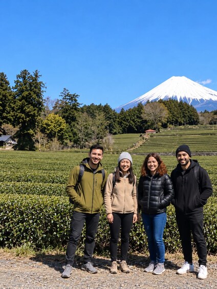 Four people standing in a field with a mountain in the background. 3