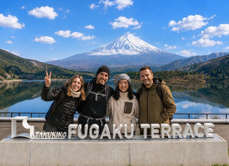 A group of people at the Fugatakufukuterrace sign with Mount Fuji in the background. 2