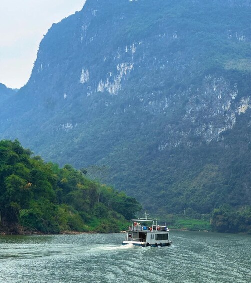 A boat on a river with dense green foliage and a steep cliff in the background. 4
