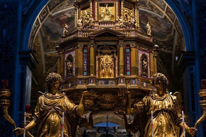 A golden statue of an angel holding a book, with a detailed shrine behind it. 3